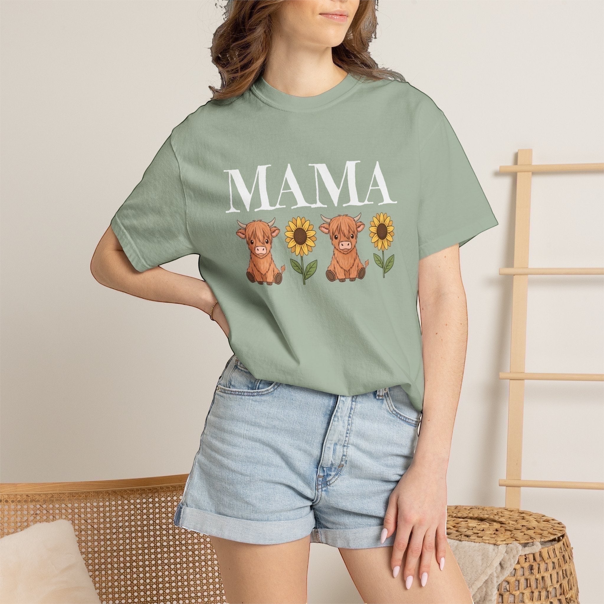 LilLlamaBean sage green cotton t-shirt with "MAMA" above two highland cows and sunflowers graphic.
