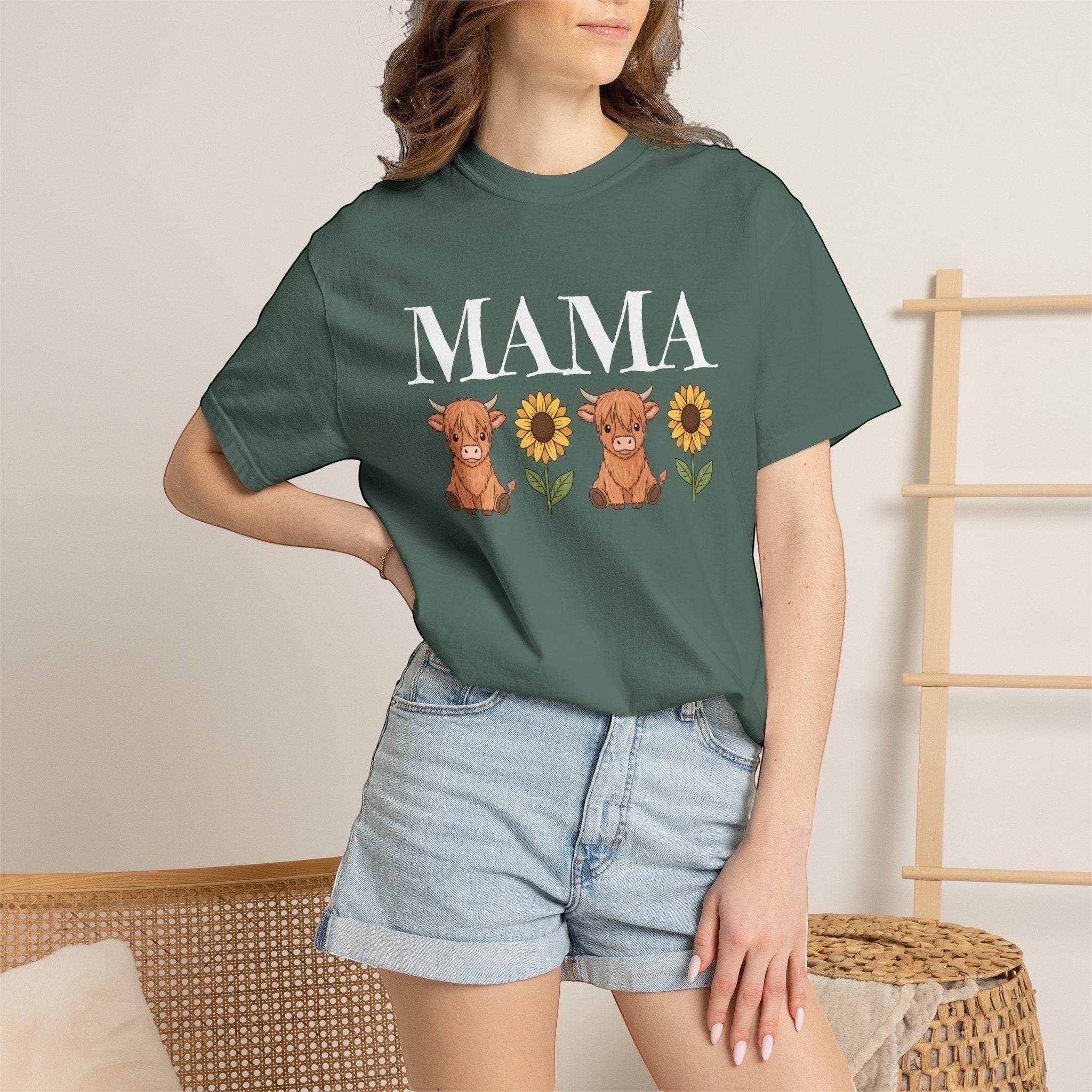 LilLlamaBean Mama Highland Cow Flower T-Shirt with two cows and sunflowers on a green tee.